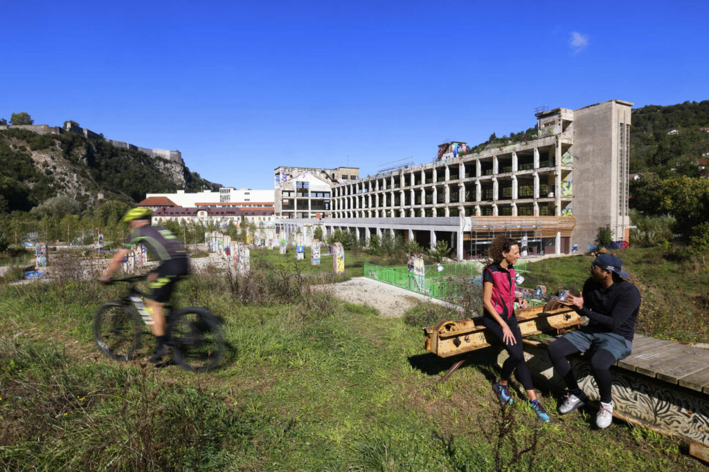 Deux coureurs et un cycliste en VTT posant devant la base outdoor